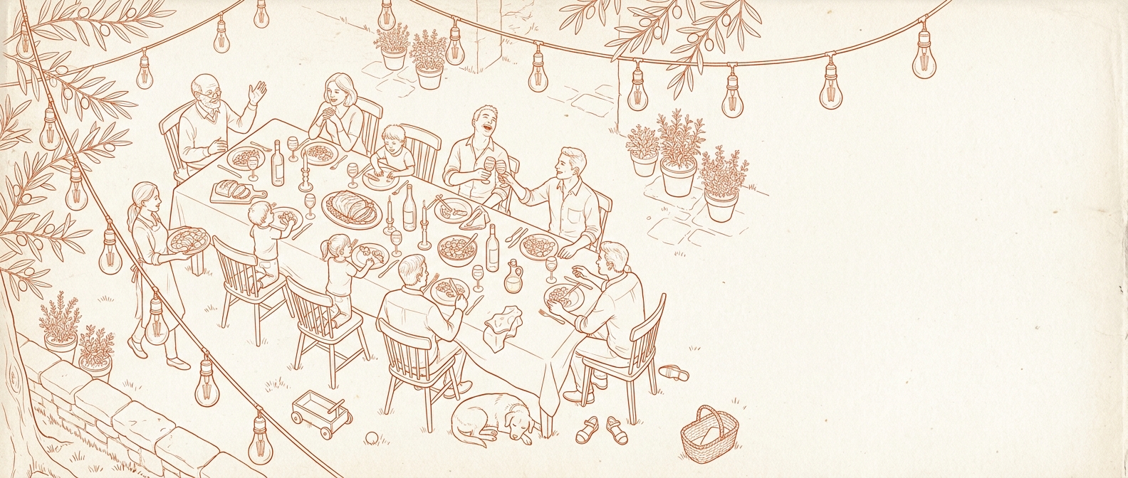Family gathered around a long outdoor table at dusk, sharing food and wine